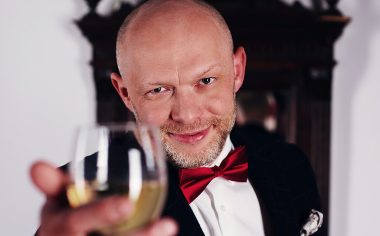 starszy mężczyzna w garniturze pozuje z kieliszkiem wina