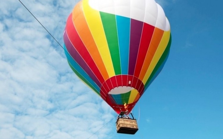 uśmiechnięta kobieta wychyla się z gondoli podczas lotu balonem