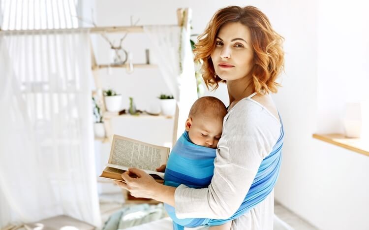 kobieta czyta książkę nosząc dziecko w chuście