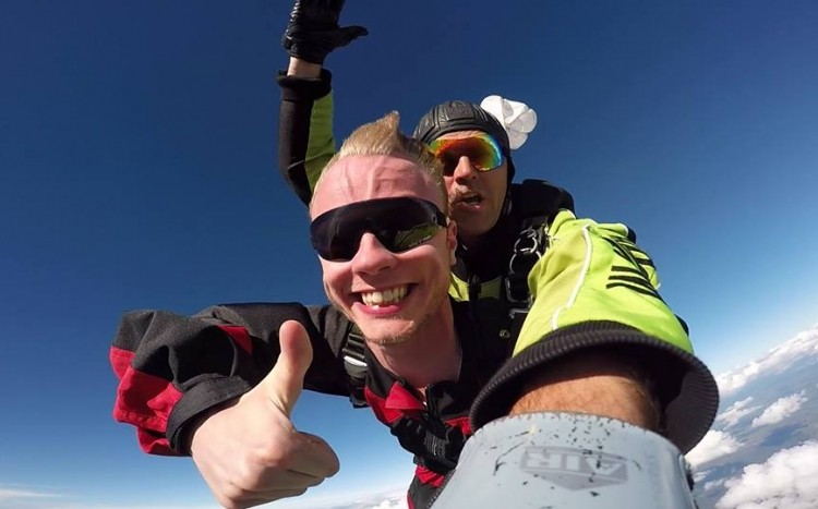 Mężczyzna wykonujący gest OK podczas lotu na spadochronie