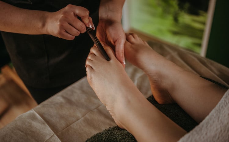 Masażystka wykonuje masaż stóp