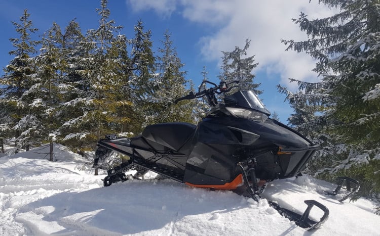 czarny skuter śnieżny w lesie