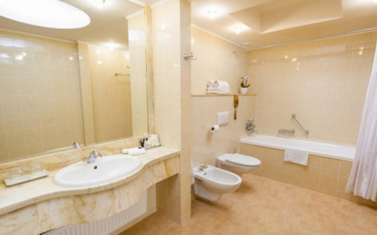 jasna łazienka z dużym lustrem, wanną, pisuarem i toaletą w hotelu
