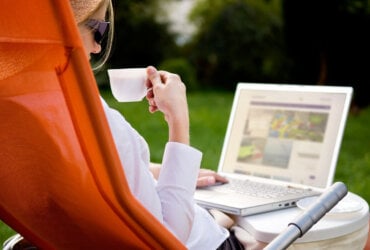 Kobieta korzystająca z laptopa trzymająca filiżankę kawy