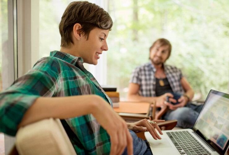 Kobieta korzystająca z laptopa, oraz mężczyzna trzymający kubek