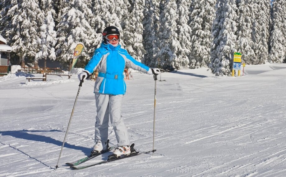 kobieta w średnim wieku pozuje z nartami na tle ośnieżonych drzew