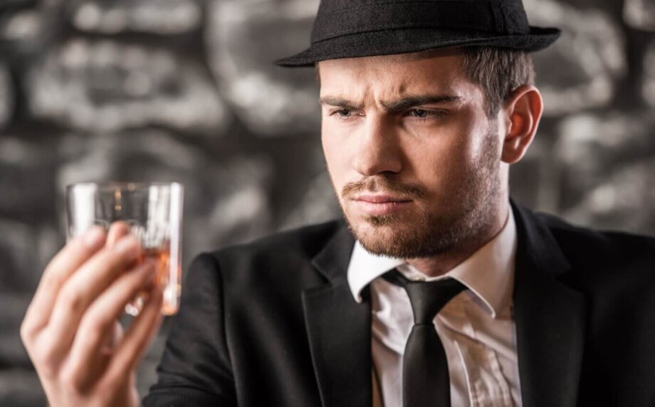 elegancko ubrany mężczyzna degustuje whisky