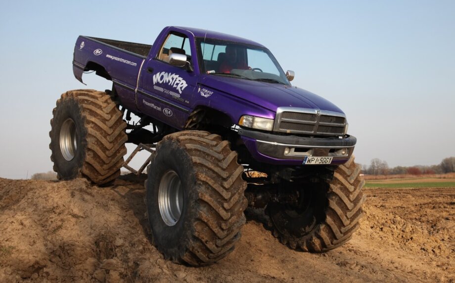 fioletowy monster truck pokonuje piaszczyste wzniesienie