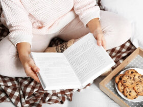 kobieta czyta książkę siedząc na łóżku