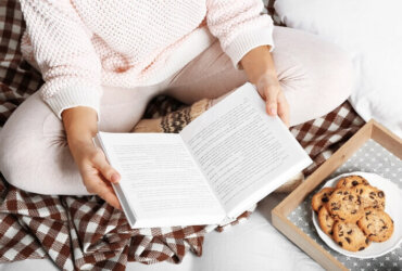 kobieta czyta książkę siedząc na łóżku