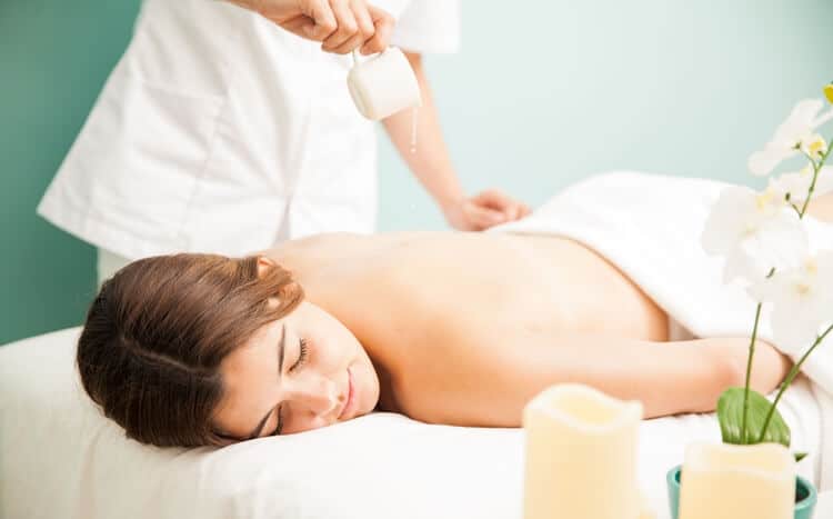 masażystka wylewa olejek ze świecy do masażu na plecy kobiety