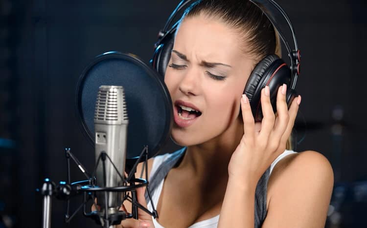 portret kobiety śpiewającej do mikrofonu w studio nagraniowym
