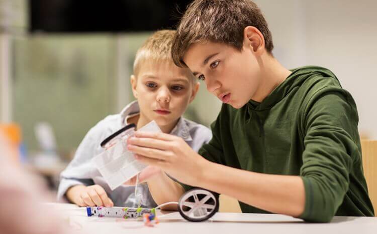 chłopcy budują robota z klocków lego