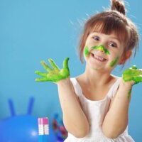 mała dziewczynka z rękami i buzią ubrudzonymi farbą