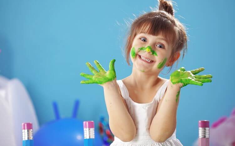 mała dziewczynka z rękami i buzią ubrudzonymi farbą