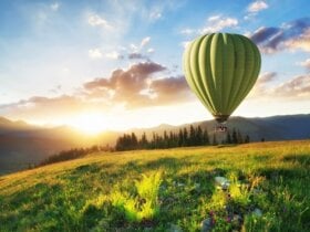 zielony balon na ogrzewane powietrze leci w górach na tle zachodu słońca