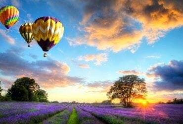 balony na ogrzewane powietrze lecące o zachodzie słońca nad wrzosowiskiem