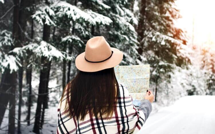 kobieta zimą w lesie trzyma w rękach mapę widok tyłem,