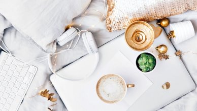 laptop, kawa i słuchawki na łóżku widok z góry