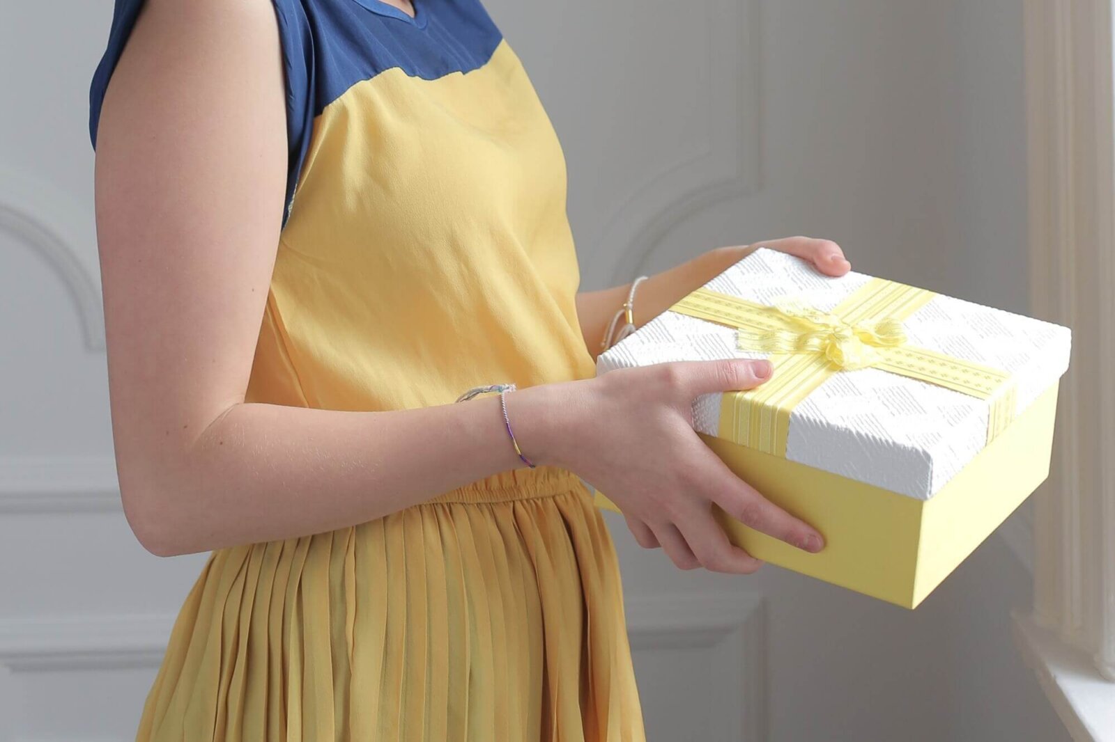 kobieta w żółtej sukience trzymająca prezent