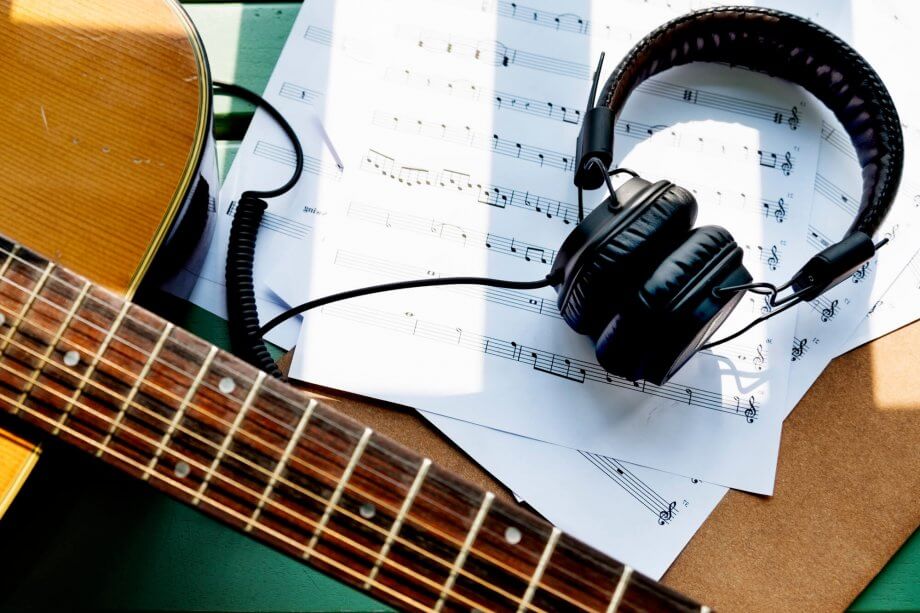 Gitara, słuchawki oraz kartki z zapisanymi nutami