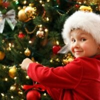 Dziecko w czapce Mikołaja ubierające choinkę