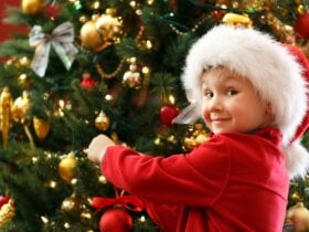 Dziecko w czapce Mikołaja ubierające choinkę