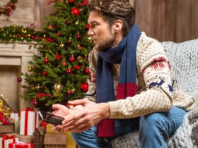 Mężczyzna trzymający w ręku telefon pośród świątecznych ozdób