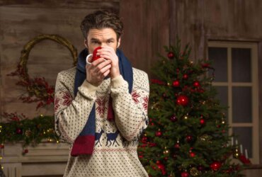 Mężczyzna trzymający kubek na tle świątecznej choinki