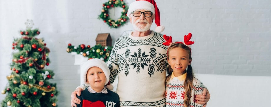Dziadek z wnukami na tle choinki oraz ozdób świątecznych