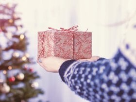 Kobieta trzymająca w rękach prezent na tle choinki świątecznej