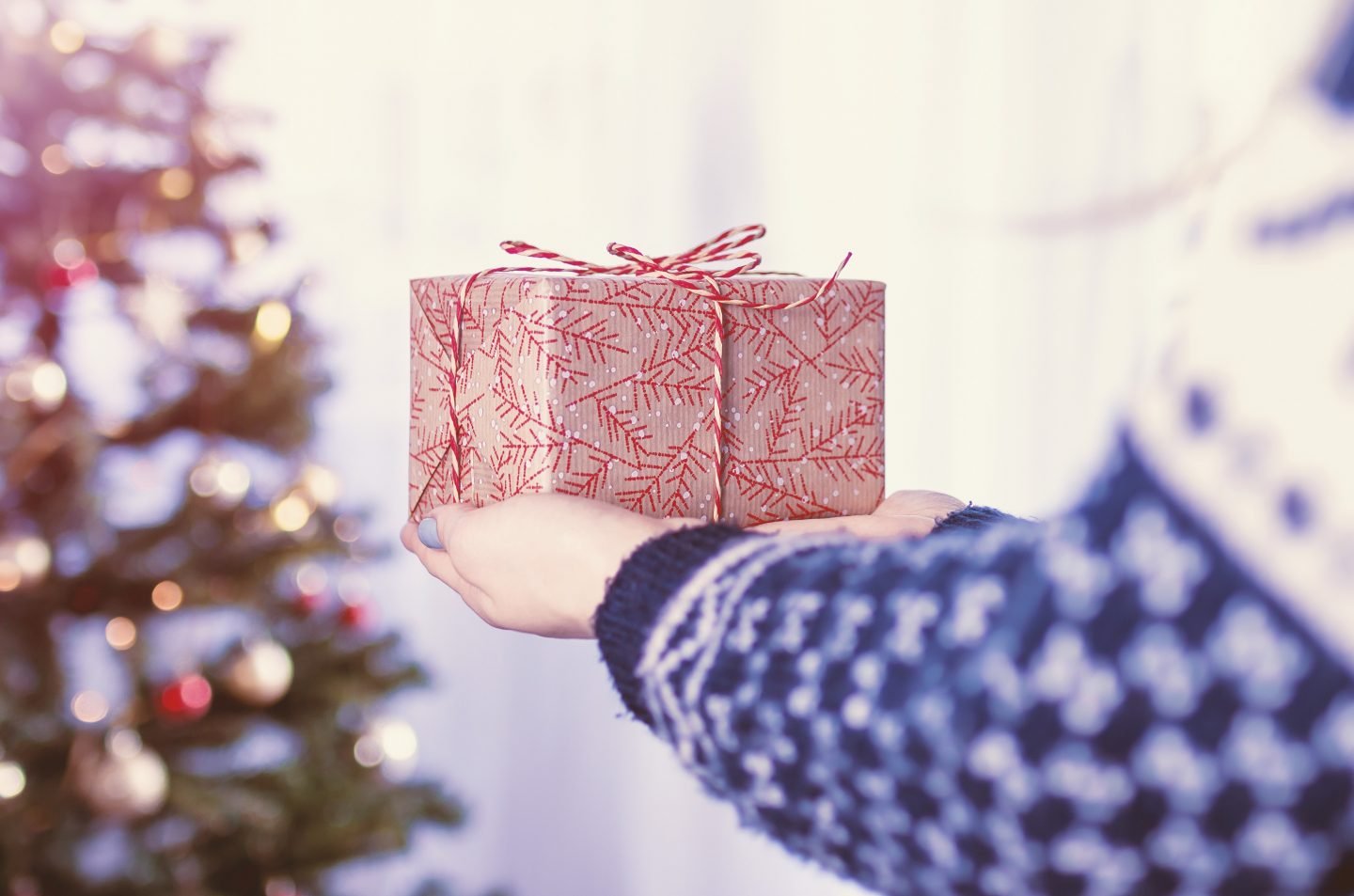 Kobieta trzymająca w rękach prezent na tle choinki świątecznej