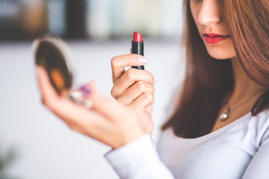 kobieta maluje usta czerwoną szminką