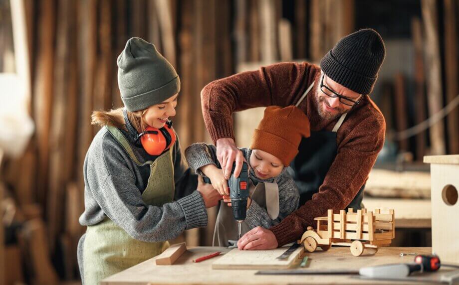 Tata z dziećmi tworzy prezent DIY  z drewna