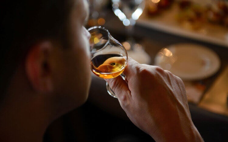 Mężczyzna wąchający whisky w szklance