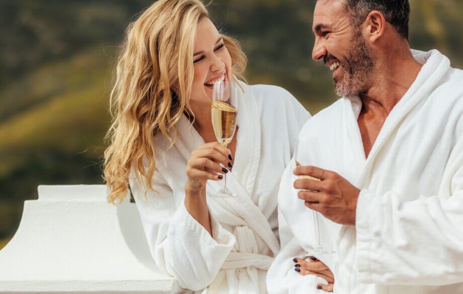 Para zakochanych w szlafrokach i z lampkami szampana podczas pobytu w SPA