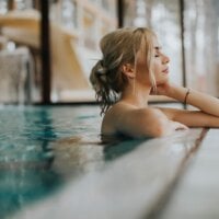 Młoda kobieta o blond włosach relaksuje się w basenie SPA
