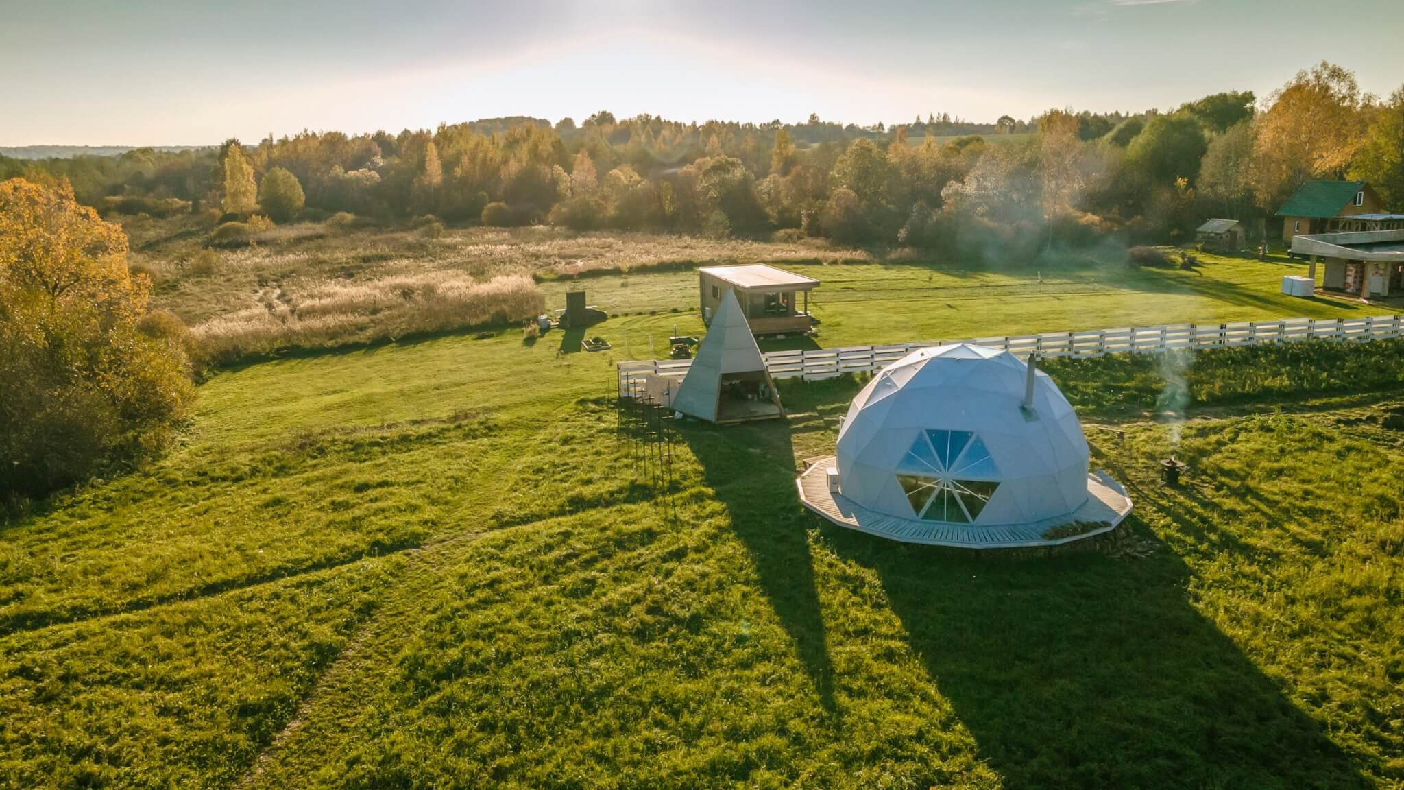 Widok z lotu ptaka na namioty glampingowe. Wokół las i zieleń.