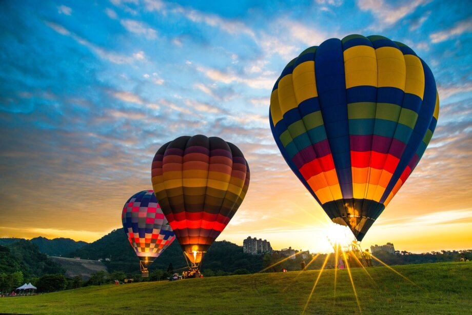 Trzy balony na ogrzewane powietrze gotowe do lotu podczas wschodu słońca 