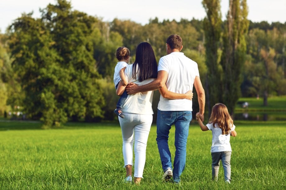 Szczęśliwa rodzina, czyli mama, tata i dwójka dzieci, spacerująca po parku