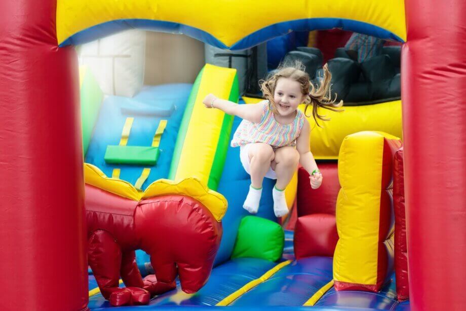 Dziewczynka skacząca na kolorowym dmuchanym zamku w sali zabaw
