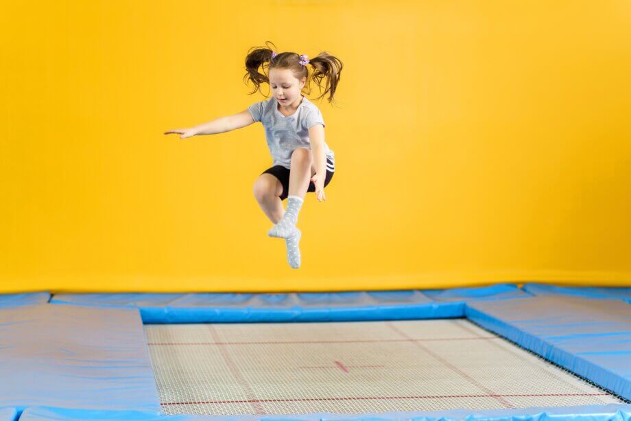 Szczęśliwa dziewczynka w dwóch kucykach skacząca na trampolinie