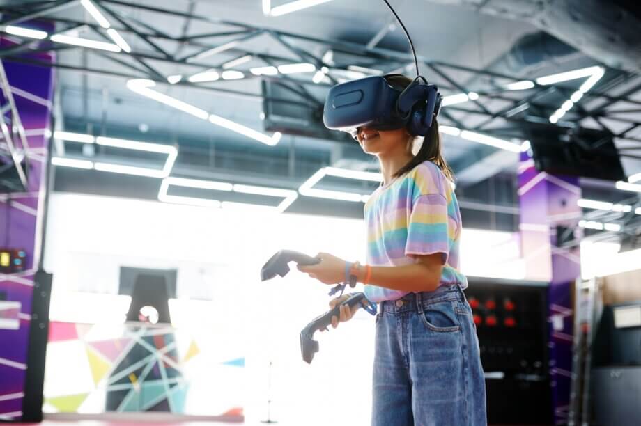 Dziewczynka w goglach VR trzymająca w rękach joysticki