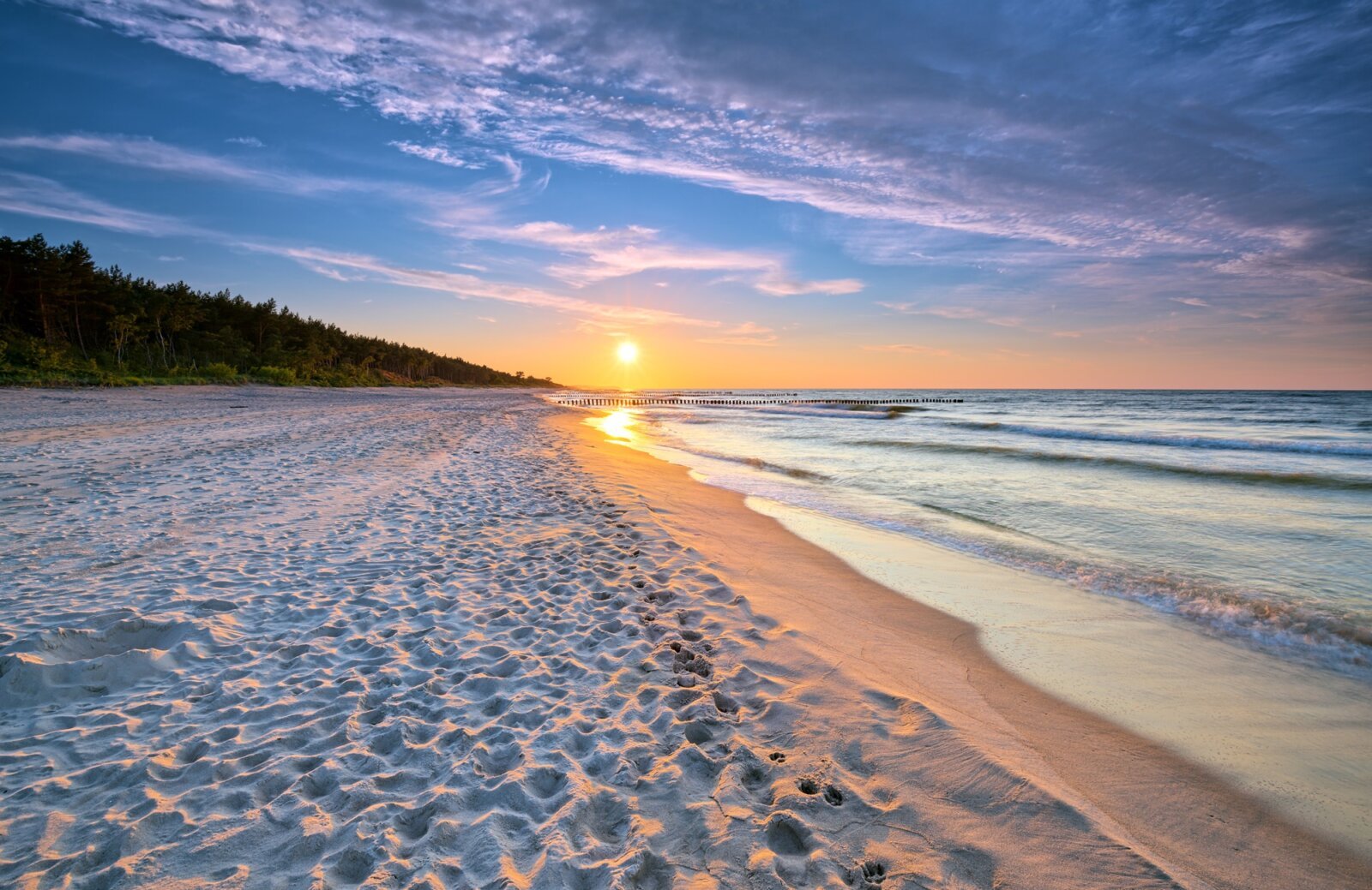 Zachodzące słońce na linii piaszczystej plaży i morza