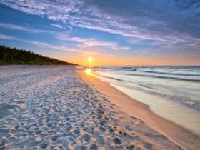 Zachodzące słońce na linii piaszczystej plaży i morza