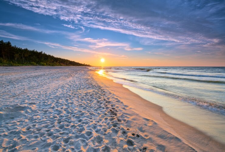 Zachodzące słońce na linii piaszczystej plaży i morza