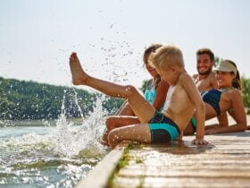 Szczęśliwa rodzina chlapiąca nogami wodę z drewnianego pomostu