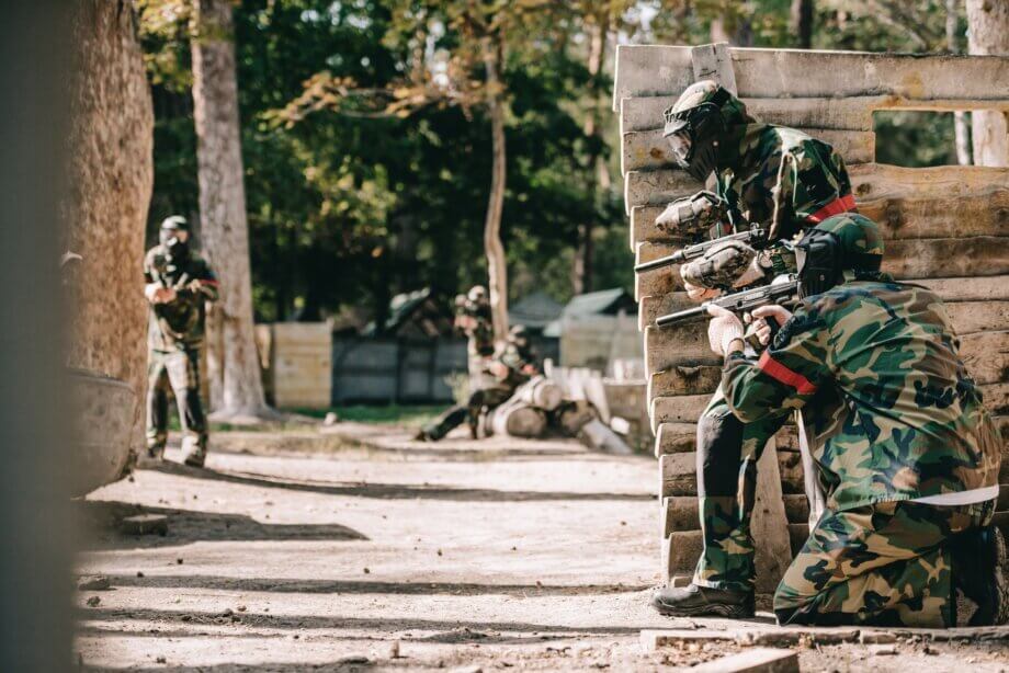 Osoby kryjące się za deskami podczas gry w paintball