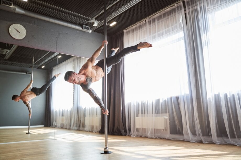 Mężczyzna robiący figurę na rurze do pole dance