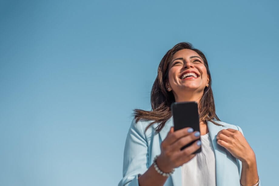 Kobieta śmiejąca się z wiadomości w telefonie